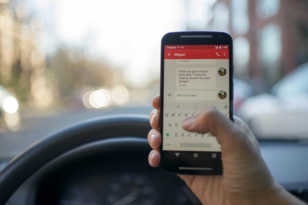 our services Close-up of a person texting on a smartphone while driving a vehicle, highlighting distracted driving.