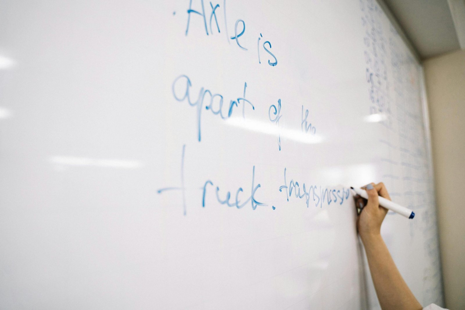 A person writing educational notes on a whiteboard, focusing on hands-on learning.