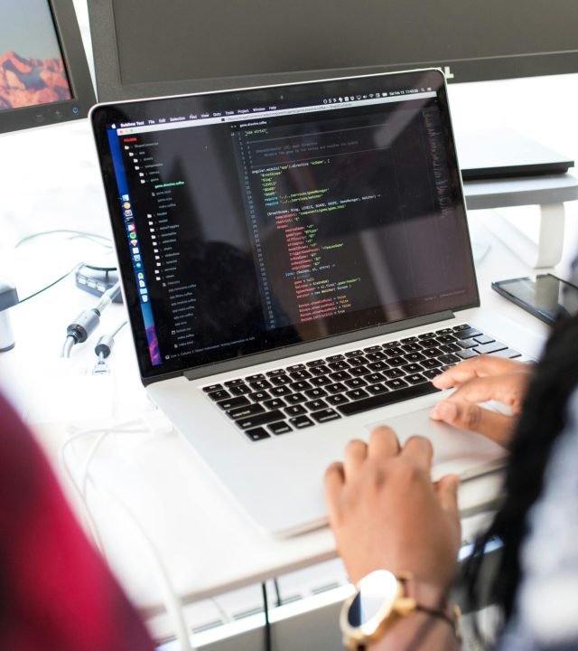 pexels photo 1181467 1181467 A woman coding on a laptop in a modern office environment with multiple monitors.
